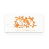 A stack of white paper gift tags with a circular hole on the left, featuring an orange floral and acorn illustration with the text 'THANKS | THE MORRIS FAMILY' printed below, shown on a plain white background.